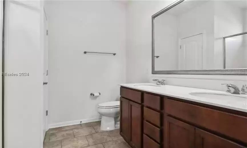 Bathroom with toilet, double sink, tile floors, and oversized vanity