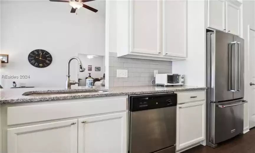 Kitchen with white cabinets, ceiling fan, light stone countertops, dark hardwood / wood-style flooring, and stainless steel appliances