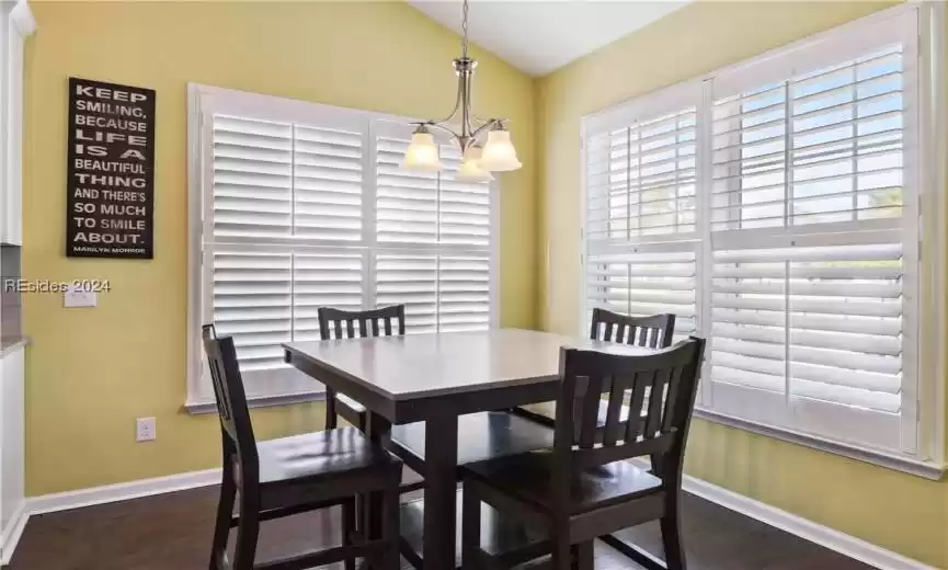 Dining room with dark hardwood / wood-style floors, a notable chandelier, and lofted ceiling