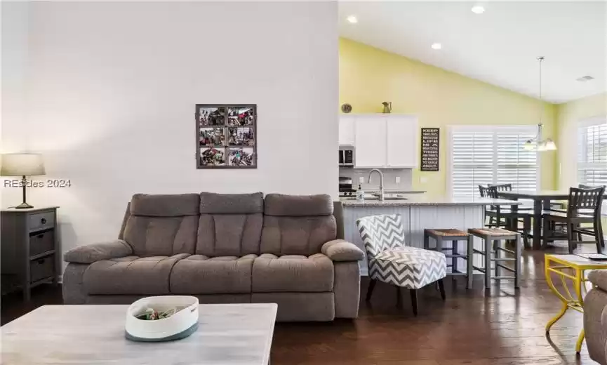 Living room featuring dark wood-type flooring, an inviting chandelier, high vaulted ceiling, and sink