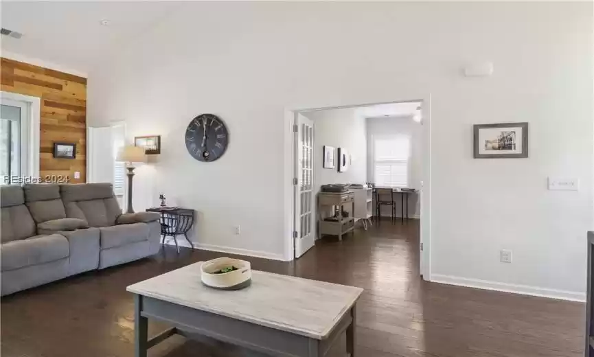 Living room with dark hardwood / wood-style floors, high vaulted ceiling, and wood walls