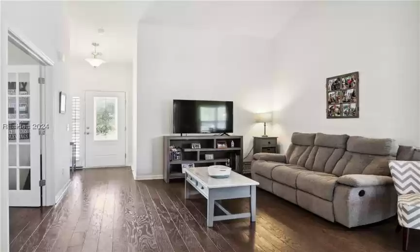Living room with high vaulted ceiling and dark wood-type flooring