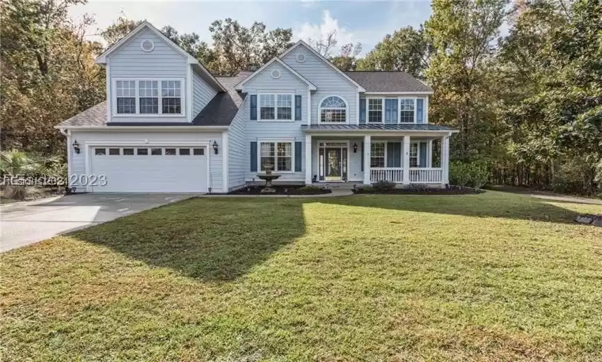 View of front of house with a front yard, a garage, and a porch