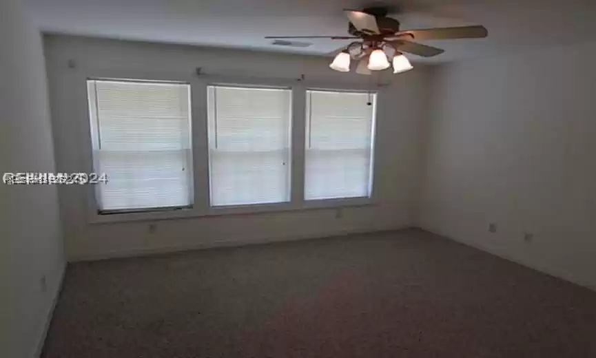 Unfurnished room featuring ceiling fan and carpet