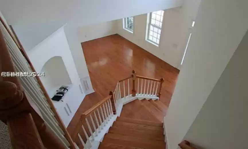 Stairway with a towering ceiling and hardwood / wood-style flooring