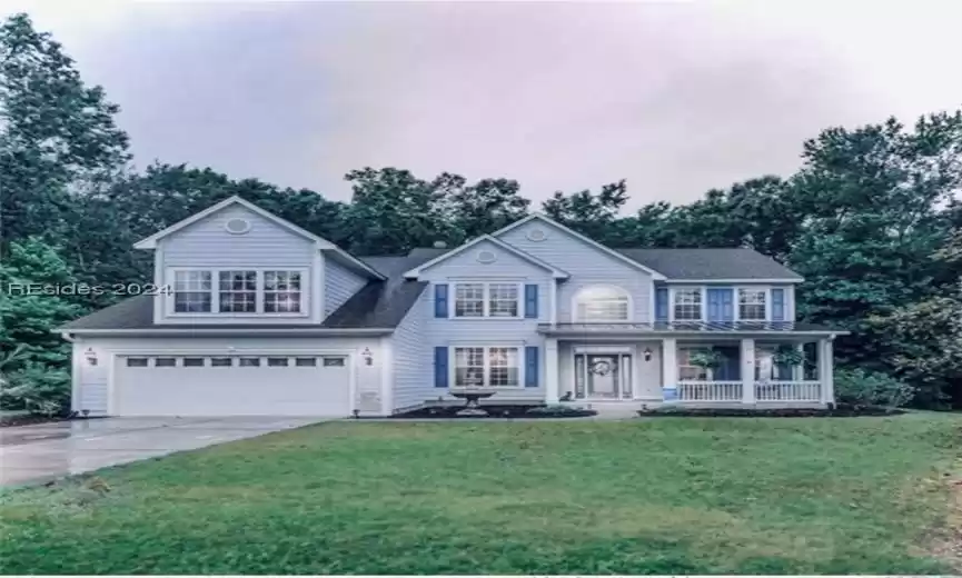 View of front of property featuring covered porch, a front yard, and a garage