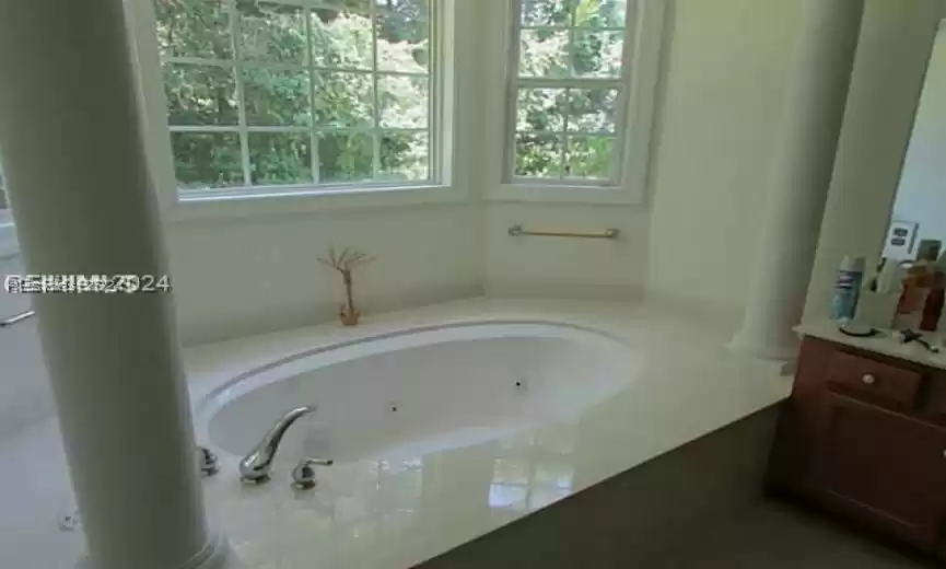 Bathroom featuring vanity, a tub, decorative columns, and a healthy amount of sunlight