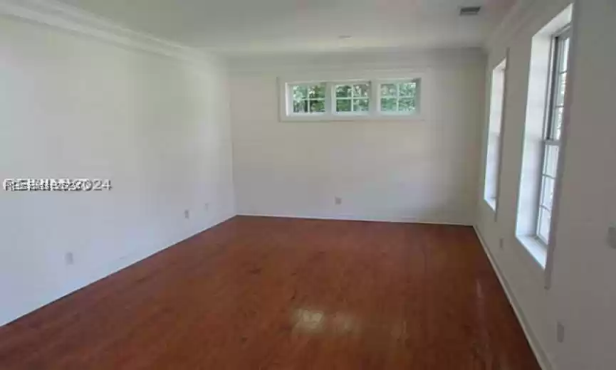 Spare room with dark hardwood / wood-style floors and crown molding