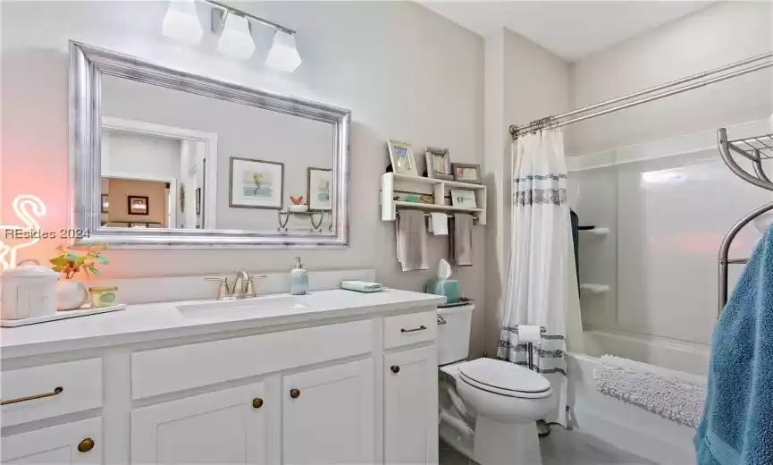 Full bathroom with vanity, toilet, shower / bath combo with shower curtain, and tile floors