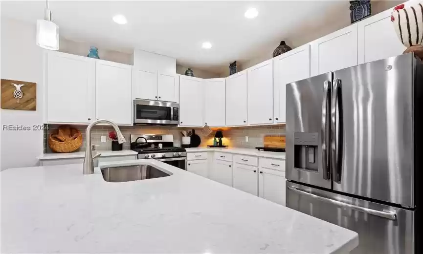 Kitchen featuring light stone countertops, stainless steel appliances, and backsplash