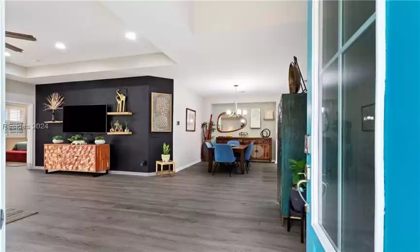 Entryway featuring hardwood / wood-style floors, ceiling fan with notable chandelier, and a raised ceiling