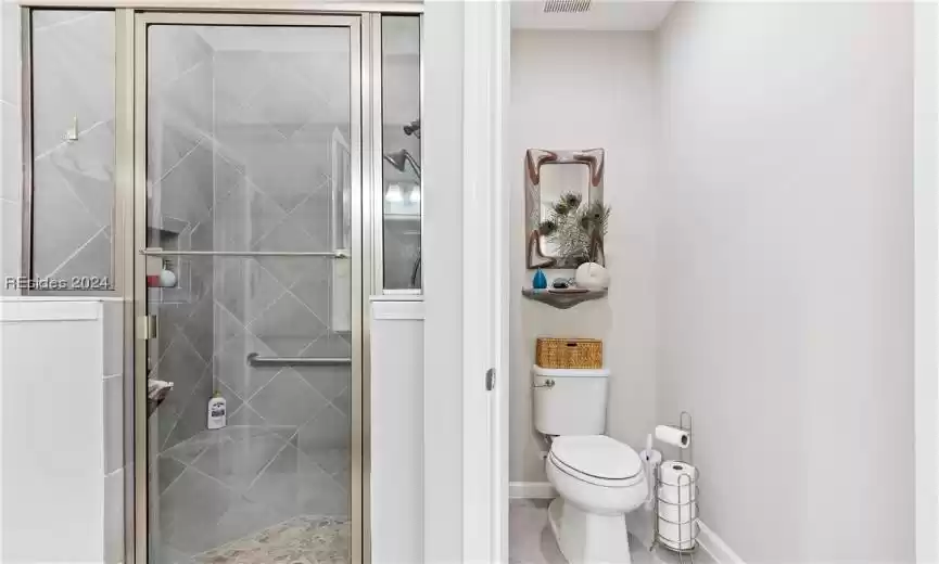 Bathroom with an enclosed shower, tile flooring, and toilet