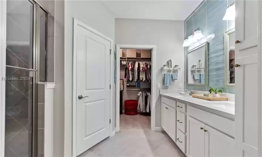 Bathroom featuring tile floors, dual vanity, and an enclosed shower
