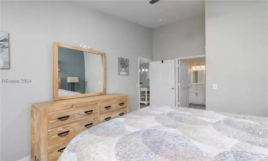 Bedroom with connected bathroom, ceiling fan with notable chandelier, and a high ceiling