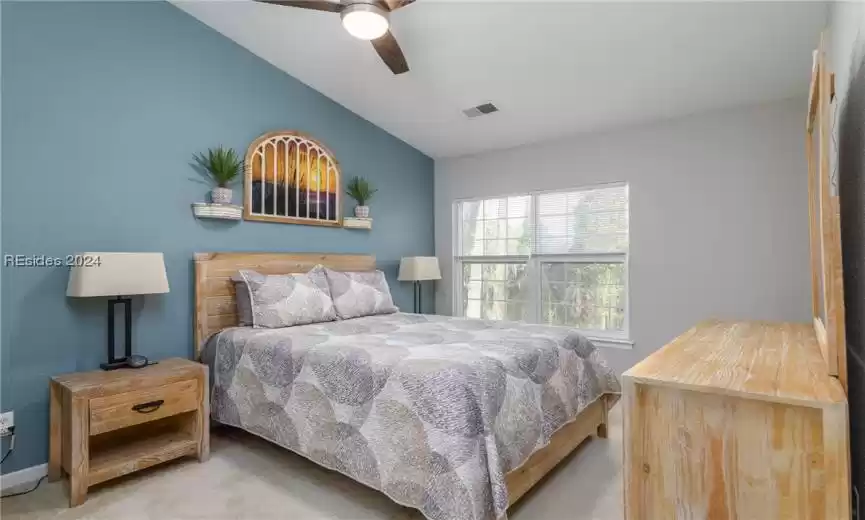 Bedroom with light carpet, ceiling fan, and vaulted ceiling