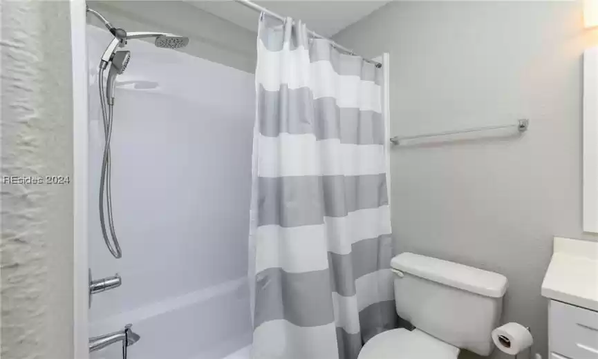 Full bathroom with shower / bath combination with curtain, vanity, and toilet