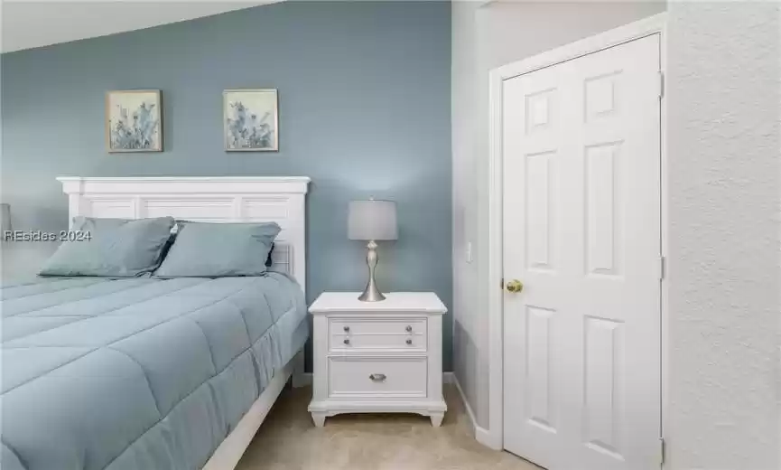 Bedroom featuring light colored carpet and vaulted ceiling