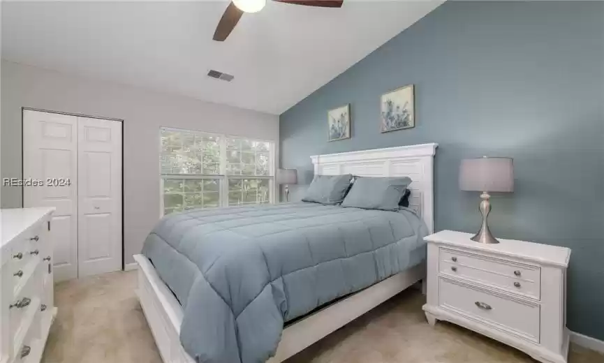 Carpeted bedroom with vaulted ceiling, a closet, and ceiling fan