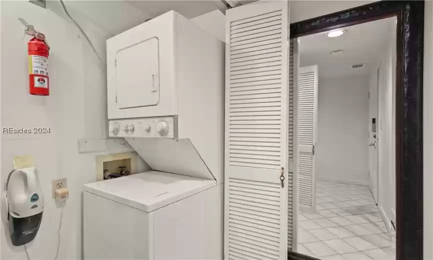 Stackable washer and dryer off of the hallway.