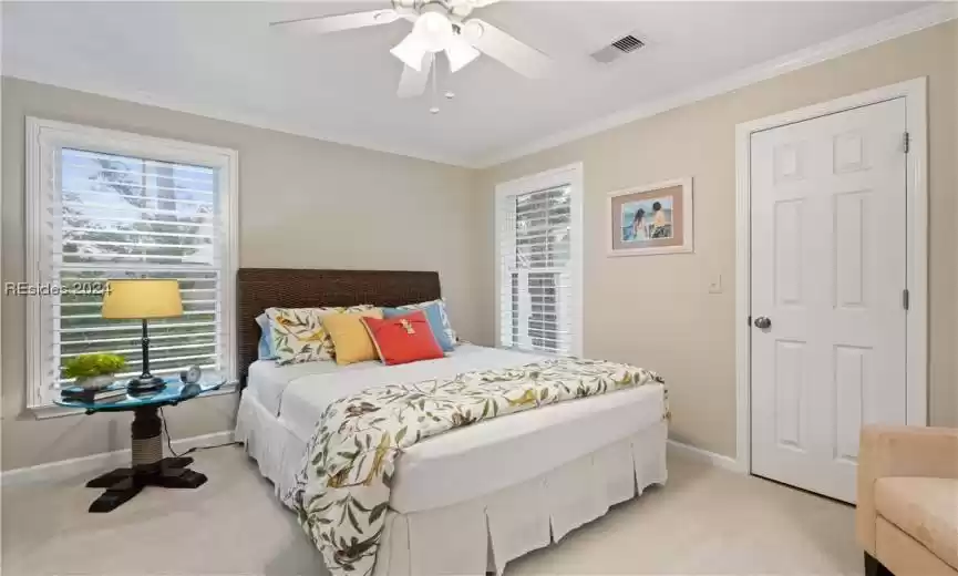 Guest bedroom with plantation shutters, crown molding and nice cedar lined walk in closet. All furniture stays except for lamps, pictures and wooden chest of drawers.