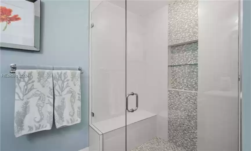 Gorgeous tiled glass enclosed shower with bench seating- this shower head has a temperature regulator to set at your heat setting.