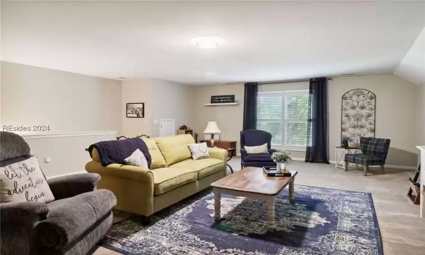 Living room with lofted ceiling and light colored carpet