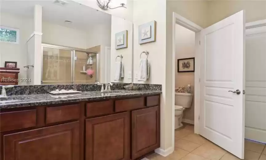 Bathroom with double vanity, tile floors, and toilet