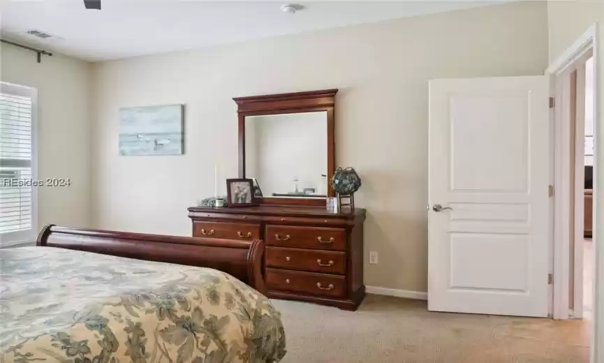 Carpeted bedroom featuring ceiling fan and multiple windows