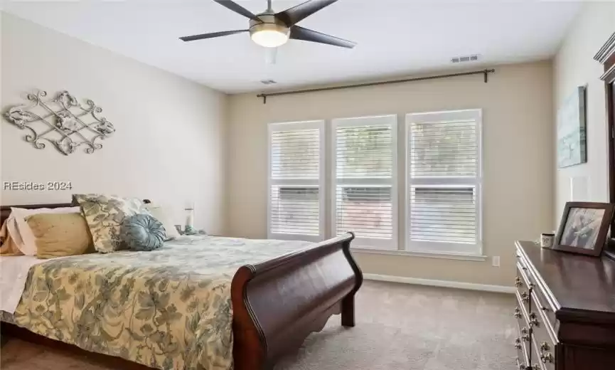 Bedroom with ceiling fan and light colored carpet