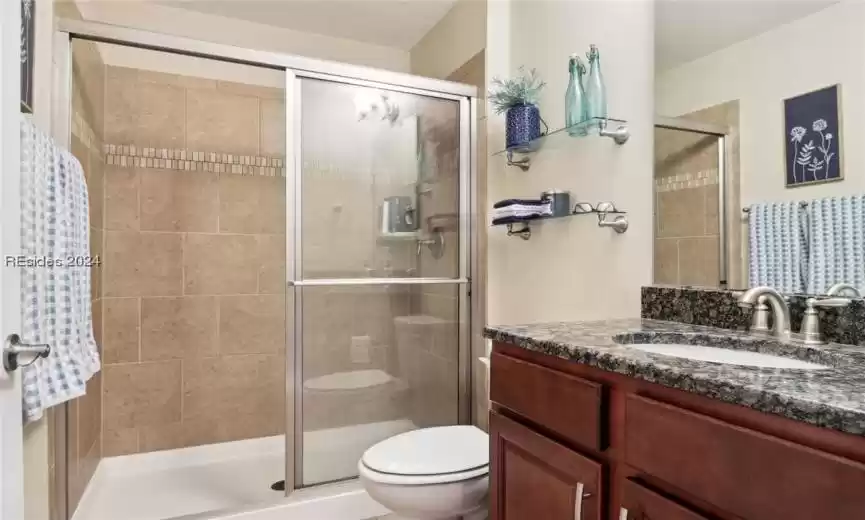 Bathroom featuring toilet, walk in shower, and vanity with extensive cabinet space