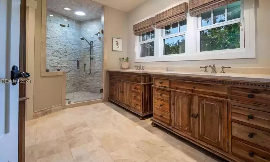Bathroom with double vanity, tile flooring, and custom walk in shower. Master bath has radiant heat flooring.