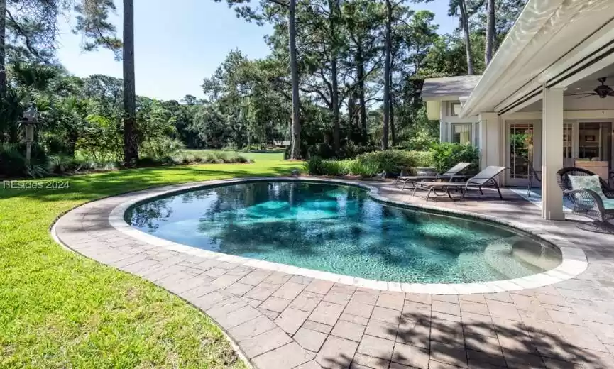 View of rebuilt swimming pool featuring a large, landscaped yard and a patio area.