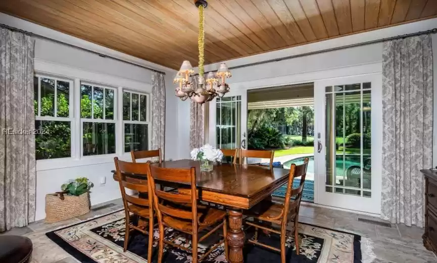 Dining space featuring a McKenzie Child's chandelier and easy access to screened porch and pool area. All furniture is included.