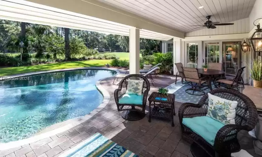 View of swimming pool featuring a patio area and ceiling fan. Porch converts to screened porch via electronic drop down.