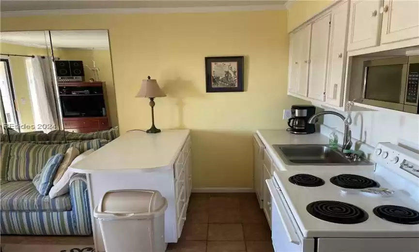 Kitchen featuring white cabinetry, dark tile flooring, white range oven, sink, and stainless steel microwave