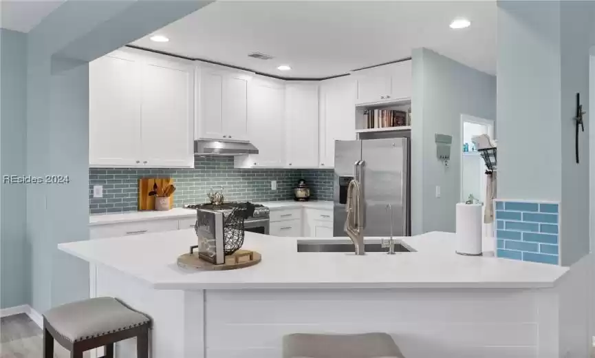 Kitchen with tasteful backsplash, high quality appliances, a breakfast bar area, and kitchen peninsula