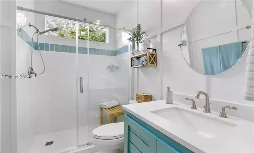 Bathroom featuring a shower with shower door, large vanity, and toilet