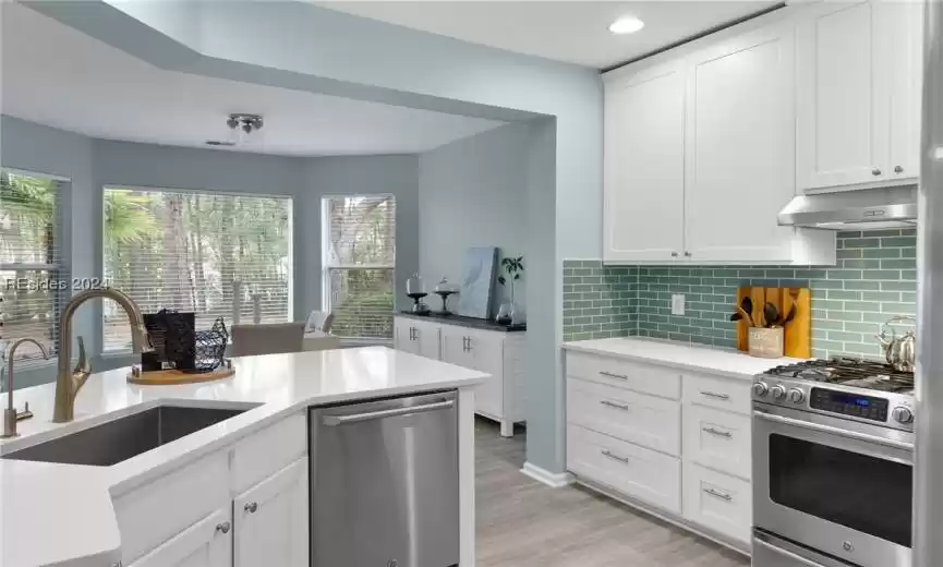 Kitchen featuring white cabinetry, backsplash, appliances with stainless steel finishes, light hardwood / wood-style flooring, and sink
