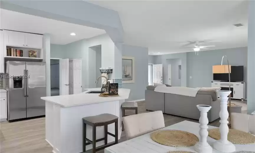 Kitchen with white cabinets, light hardwood / wood-style flooring, sink, high end fridge, and ceiling fan