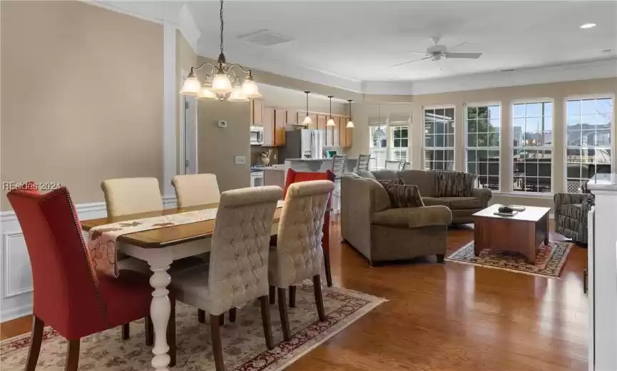 Dining room featuring ceiling fan with notable chandelier, ornamental molding, and dark hardwood / wood-style flooring