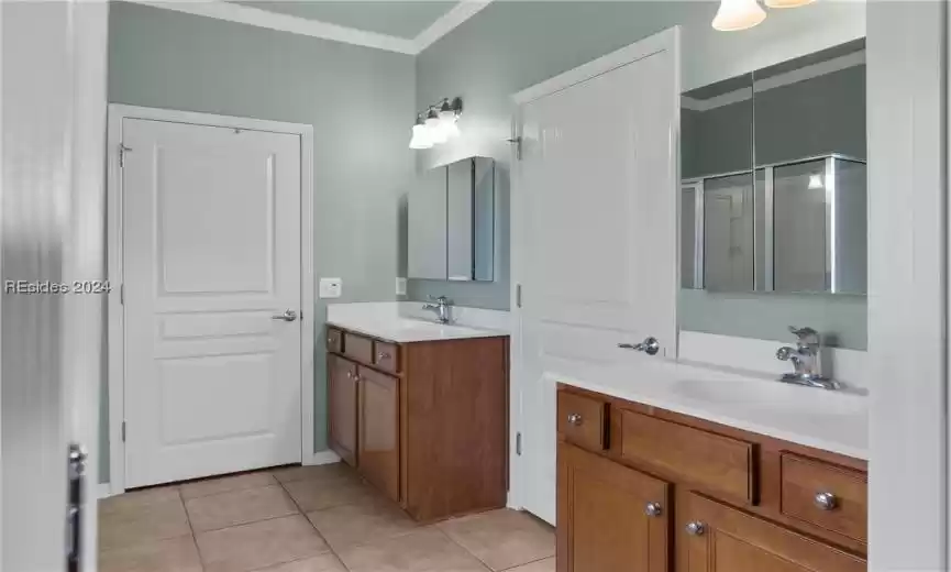 Bathroom with dual vanity, ornamental molding, and tile flooring