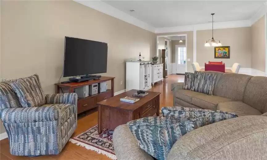 Living room with a chandelier, light hardwood / wood-style floors, and ornamental molding