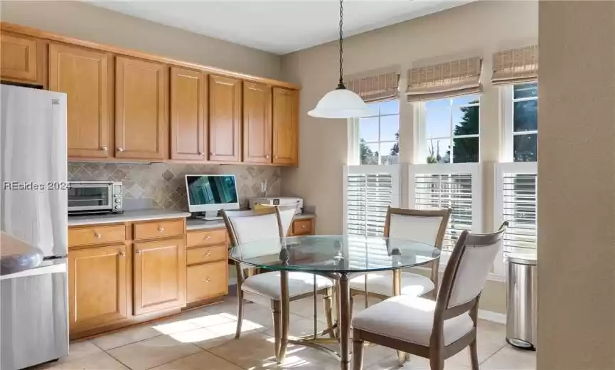Kitchen featuring light tile flooring, decorative light fixtures, stainless steel refrigerator, and tasteful backsplash