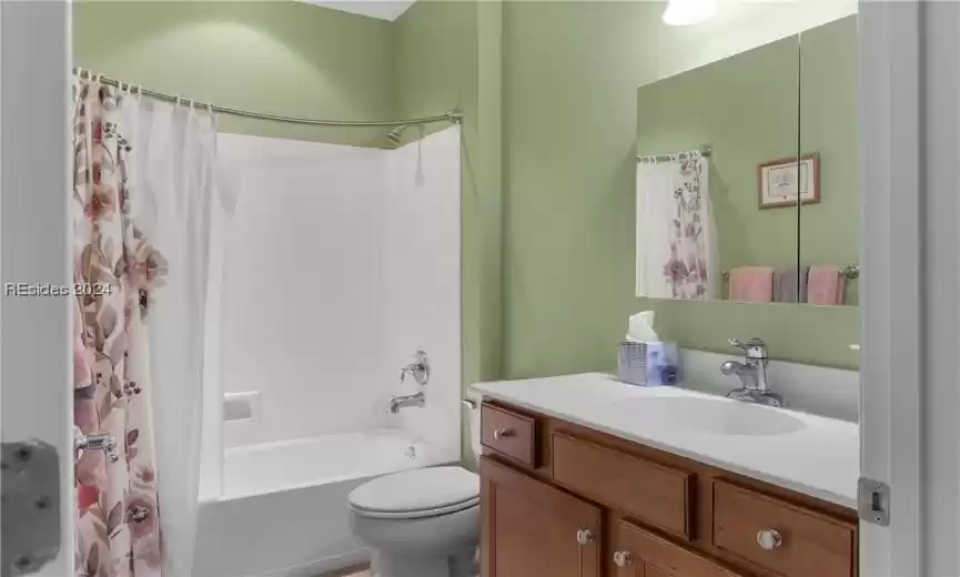 Full bathroom with shower / bath combo with shower curtain, vanity, and toilet