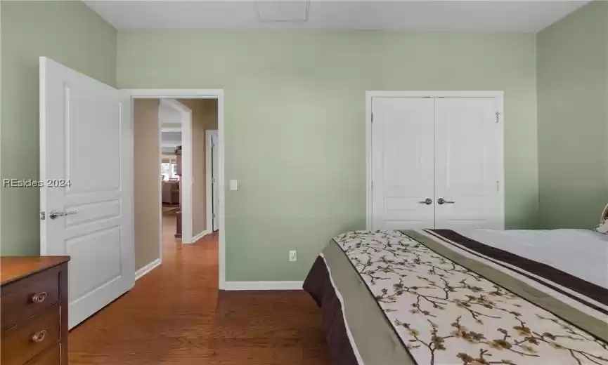 Bedroom with dark hardwood / wood-style floors and a closet