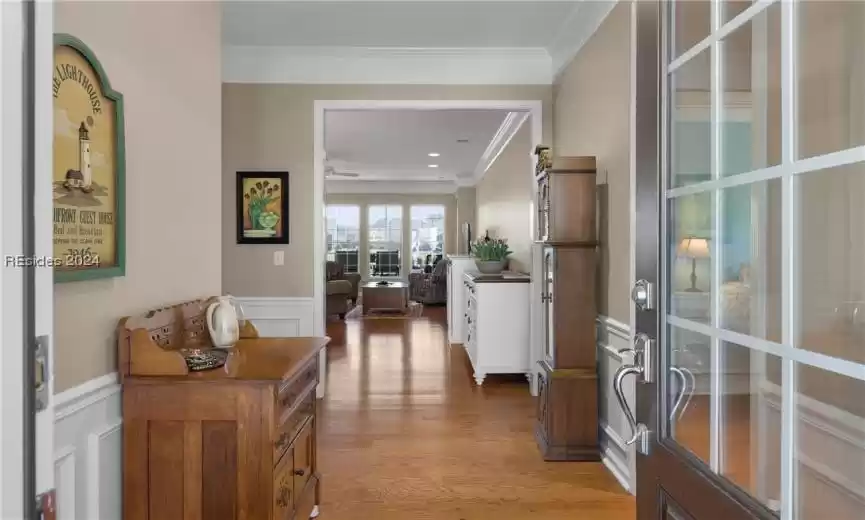 Hall with light hardwood / wood-style floors, ornamental molding, and french doors
