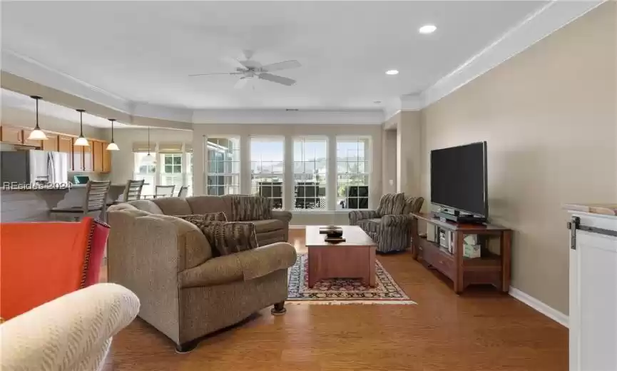 Living room featuring plenty of natural light, crown molding, ceiling fan, and hardwood / wood-style flooring