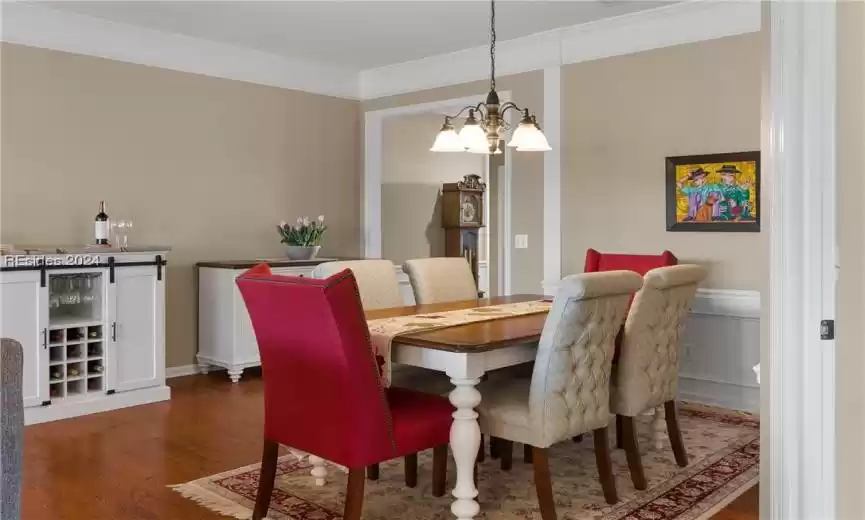 Dining space featuring dark wood-type flooring, an inviting chandelier, and crown molding