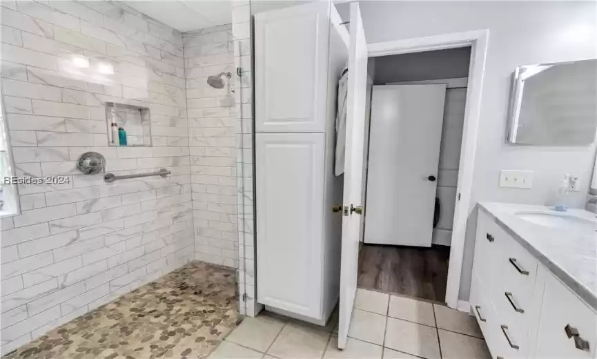 Bathroom with vanity with extensive cabinet space, tiled shower, and hardwood / wood-style floors