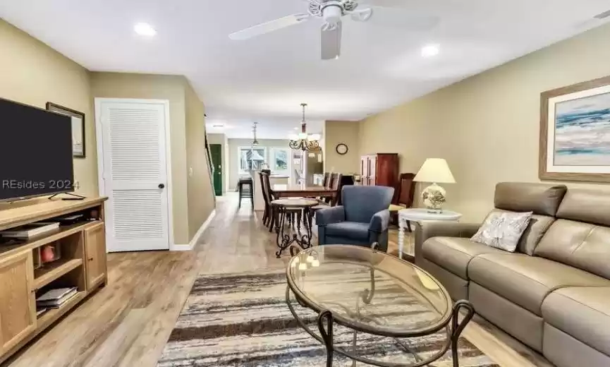 Living room with light hardwood / wood-style floors and ceiling fan with notable chandelier